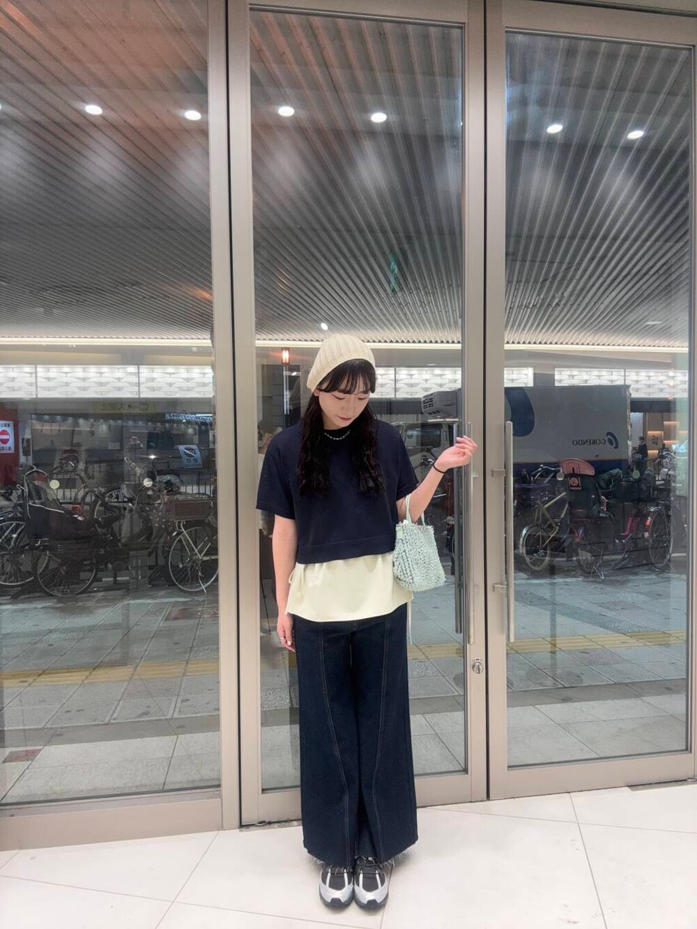 ブラック系のスニーカー、グリーン系のショルダーバッグ、ブルー系のニット/セーターを着用したレディースの春コーディネートの2枚目の写真