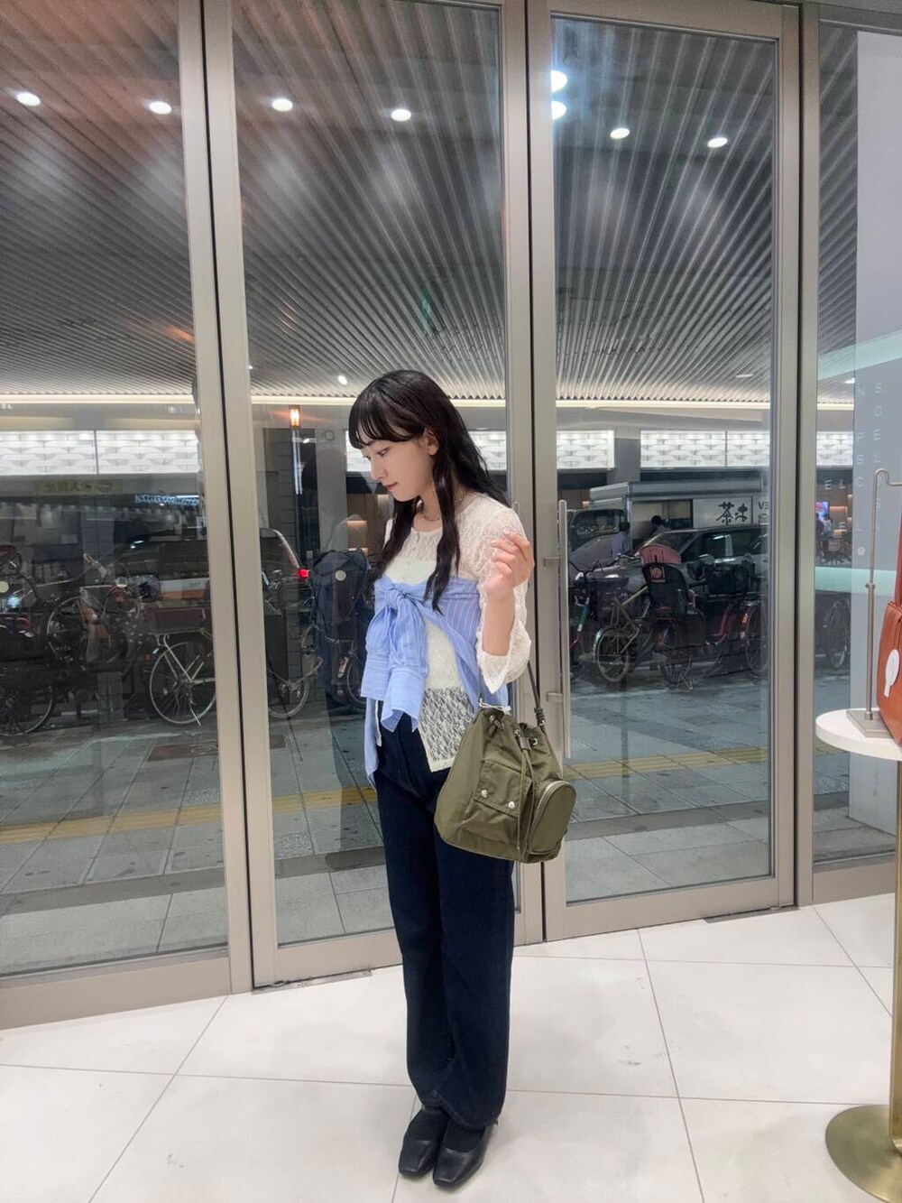 ブルー系のデニムパンツ、ブラック系のパンプス、ホワイト系のキャミソールを着用したレディースの春コーディネートの2枚目の写真