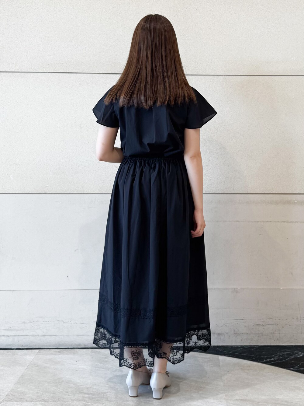 ブラック系のシャツ/ブラウス、ブラック系のスカート、ベージュ系のパンプスを着用したレディースの夏コーディネートの3枚目の写真
