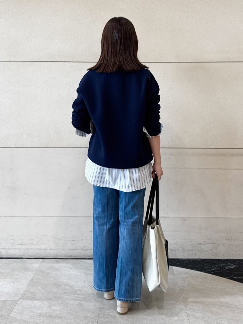 ブルー系のニット/セーター、グレー系のシャツ/ブラウス、ブルー系のデニムパンツを着用したレディースの冬コーディネートの4枚目の写真