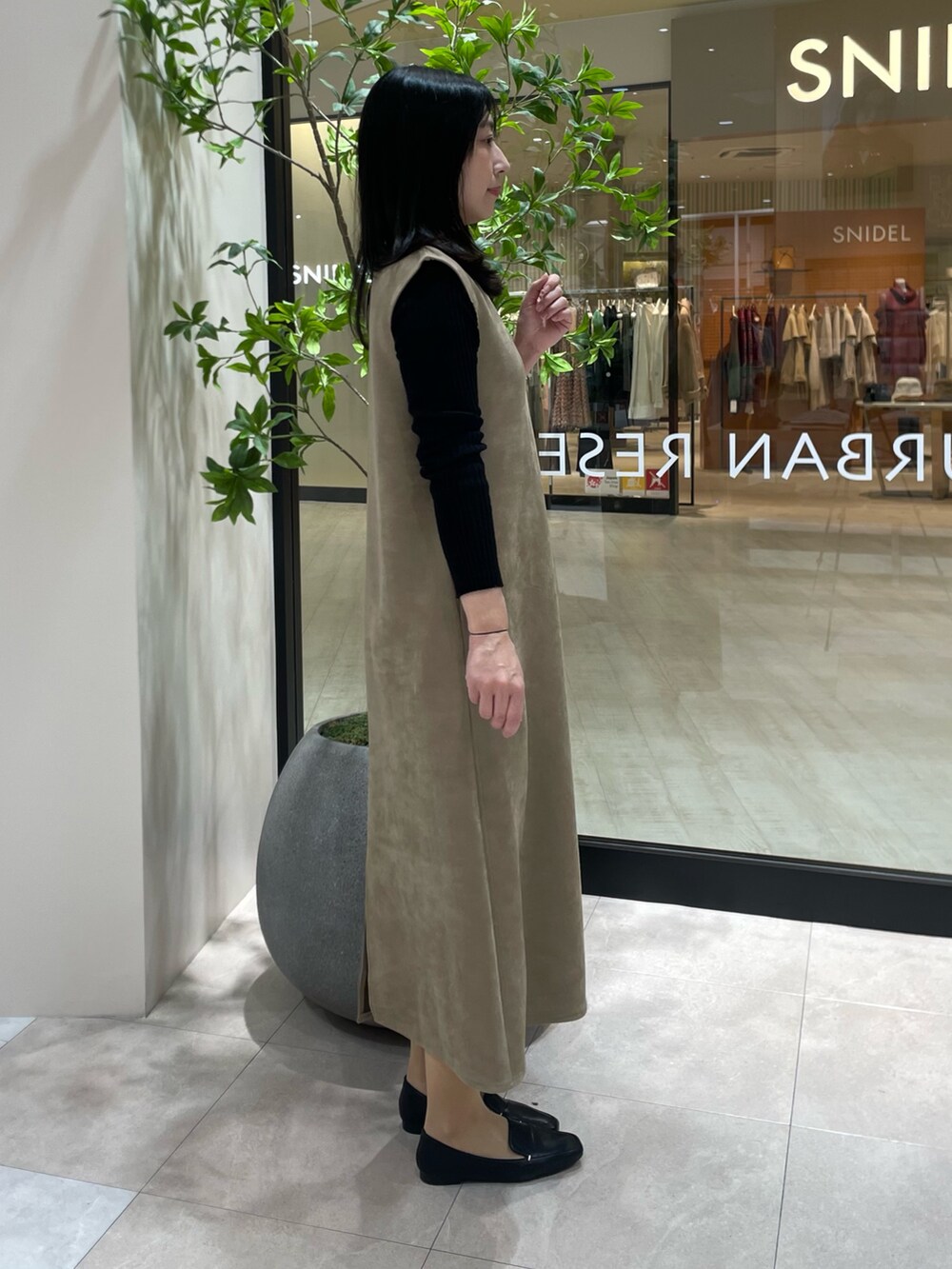 ブラウン系のワンピース、ブラック系のニット/セーター、オレンジ系のショルダーバッグを着用したレディースの秋コーディネートの3枚目の写真
