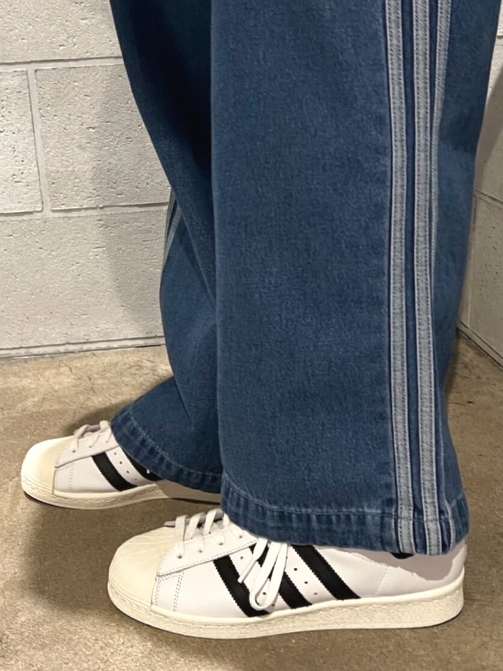 ブルー系のデニムパンツ、イエロー系のTシャツ/カットソー、ホワイト系のシューズを着用したメンズの秋コーディネートの2枚目の写真