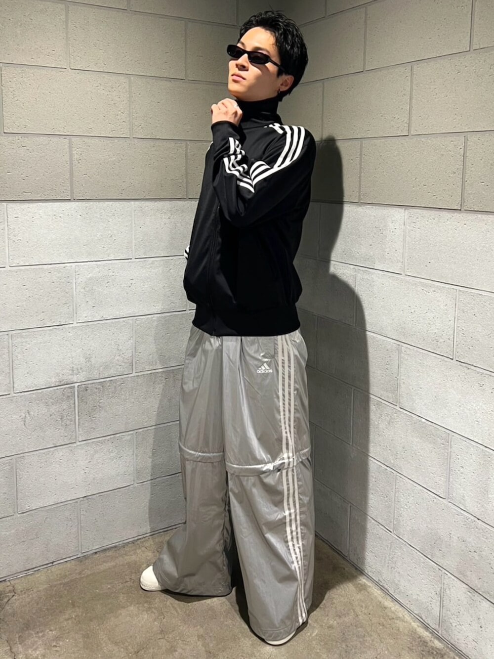 シルバー系のスウェットパンツ、ブラック系のジャージ、ホワイト系のシューズを着用したメンズの秋コーディネートの3枚目の写真