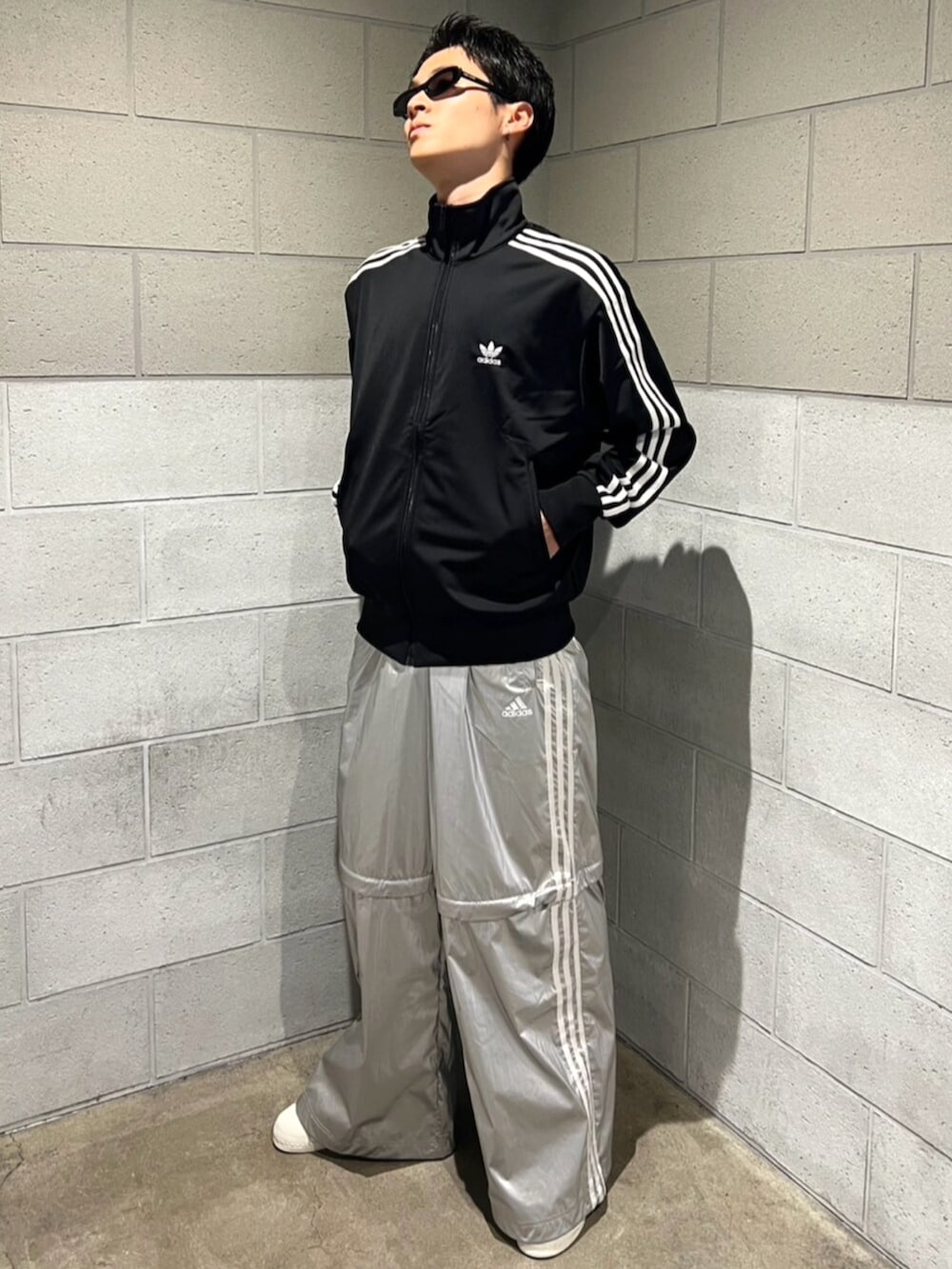 シルバー系のスウェットパンツ、ブラック系のジャージ、ホワイト系のシューズを着用したメンズの秋コーディネートの2枚目の写真