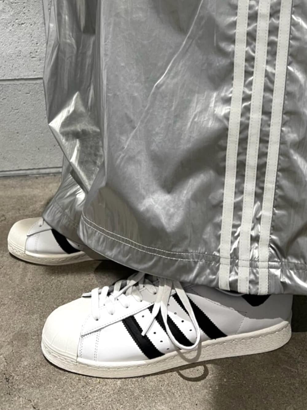 シルバー系のスウェットパンツ、ブラック系のジャージ、ホワイト系のシューズを着用したメンズの秋コーディネートの4枚目の写真