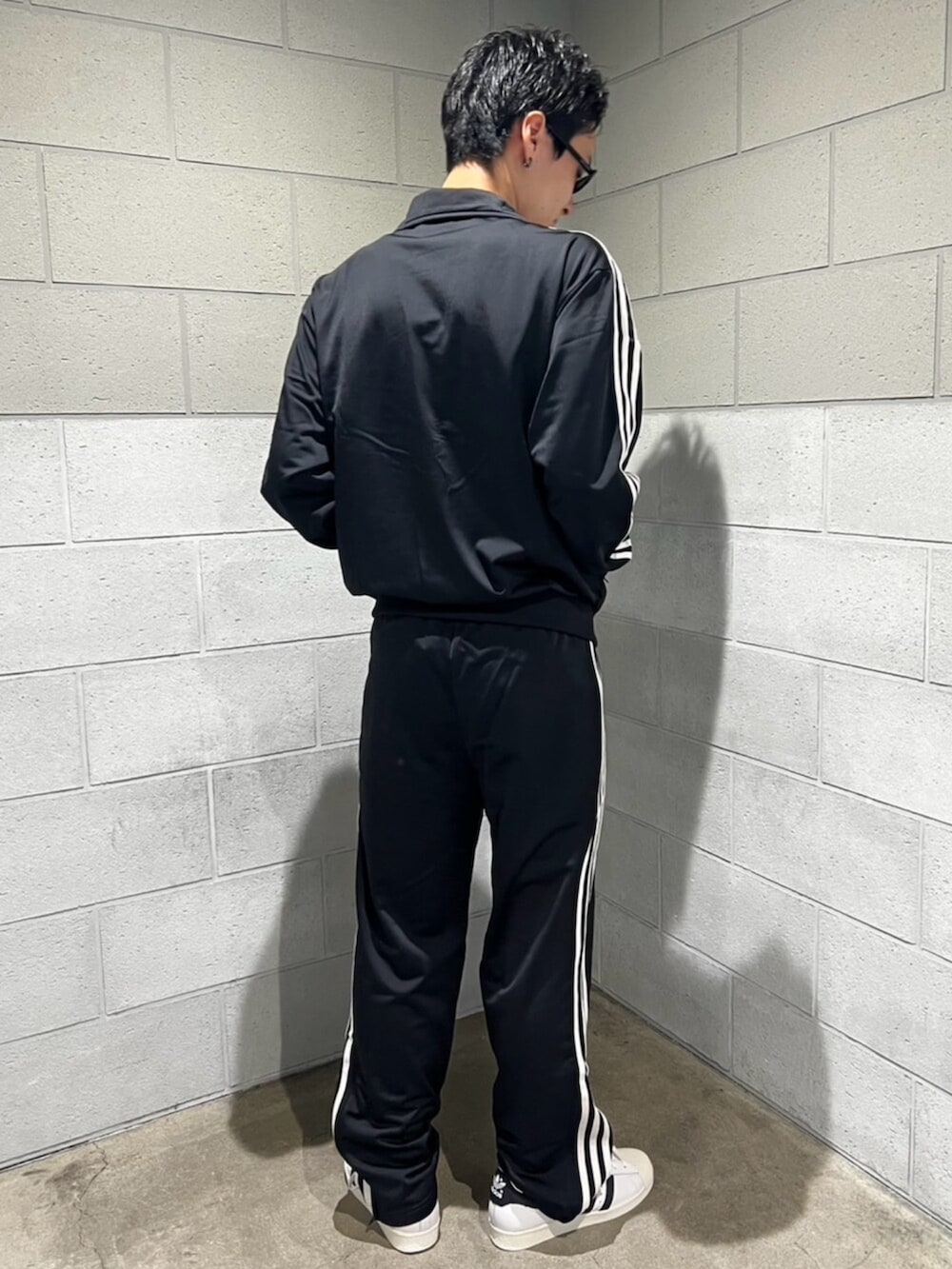 ブラック系のスウェットパンツ、ブラック系のジャージ、ホワイト系のシューズを着用したメンズの秋コーディネートの3枚目の写真