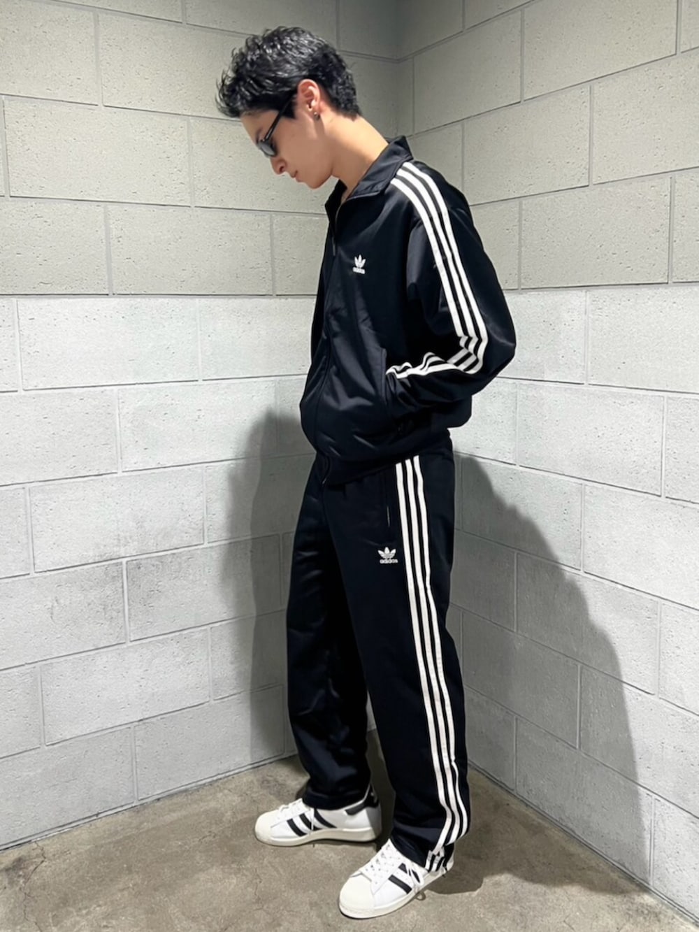 ブラック系のスウェットパンツ、ブラック系のジャージ、ホワイト系のシューズを着用したメンズの秋コーディネートの2枚目の写真