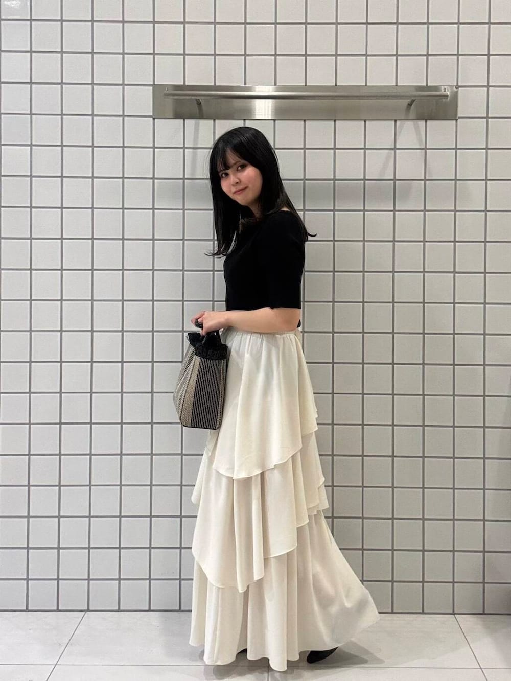 ブラック系のサンダル、ホワイト系のスカート、ブラック系のニット/セーターを着用したレディースの春コーディネートの2枚目の写真
