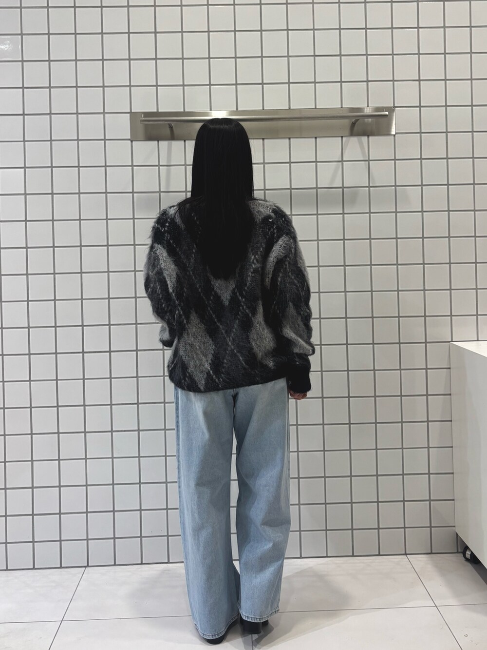 ブルー系のデニムパンツ、ブラック系のブーツ、ブラック系のニット/セーターを着用したレディースの冬コーディネートの2枚目の写真