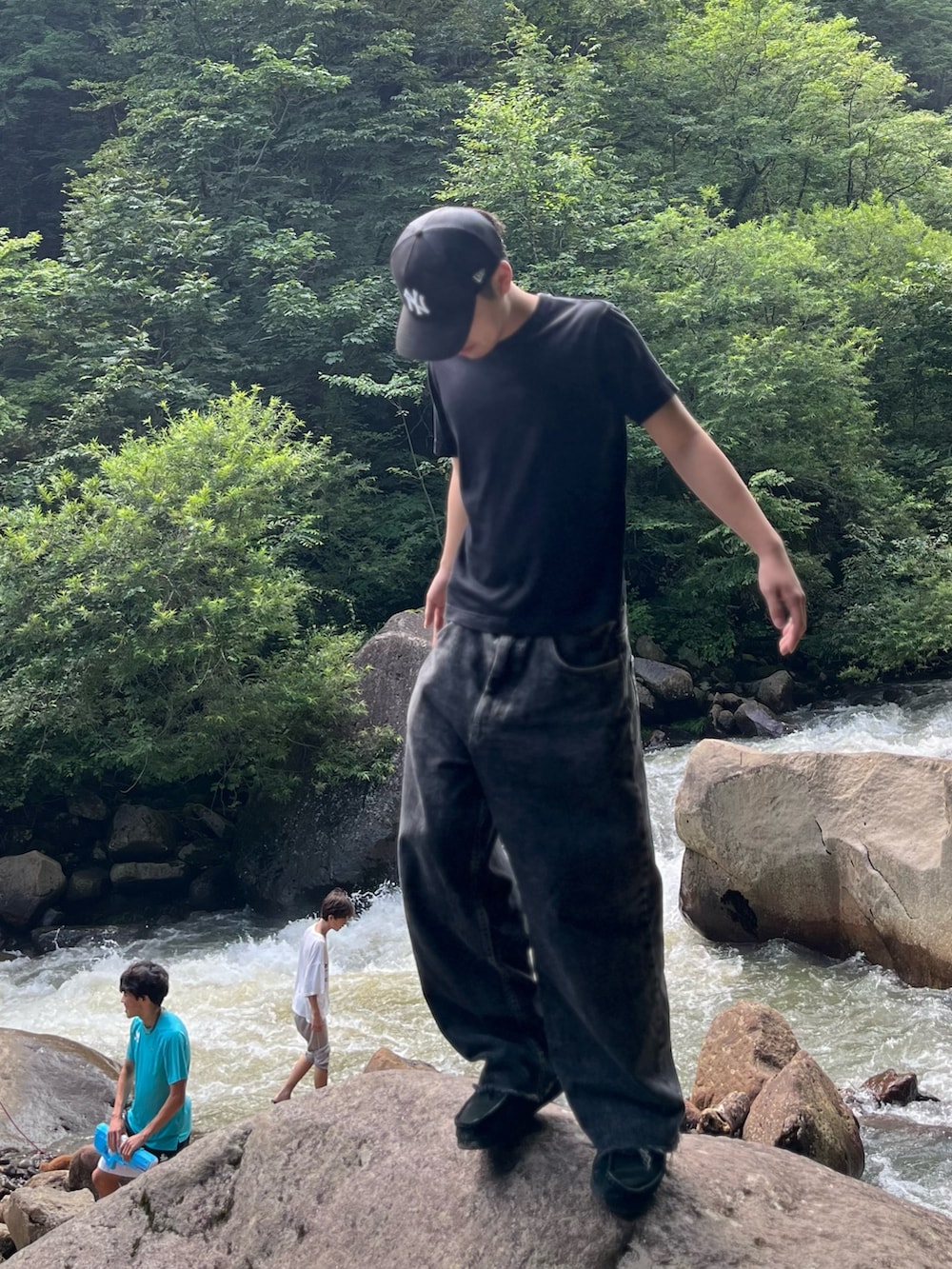 ブラック系のブーツ、ブラック系のデニムパンツ、ブルー系のキャップを着用したメンズの夏コーディネートの2枚目の写真