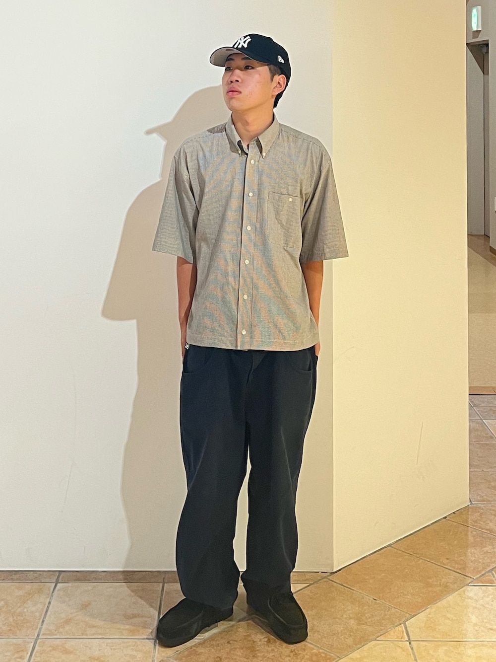 ブラック系のデニムパンツ、ブラック系のブーツ、ブルー系のキャップを着用したメンズの秋コーディネートの2枚目の写真