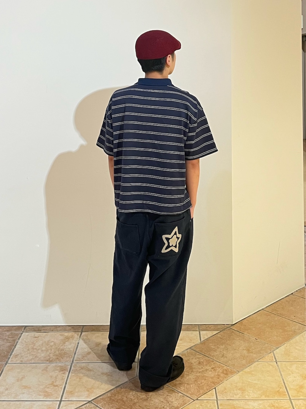 ブルー系のポロシャツ、ブラック系のデニムパンツ、レッド系のハンチング/ベレー帽を着用したメンズの夏コーディネートの2枚目の写真