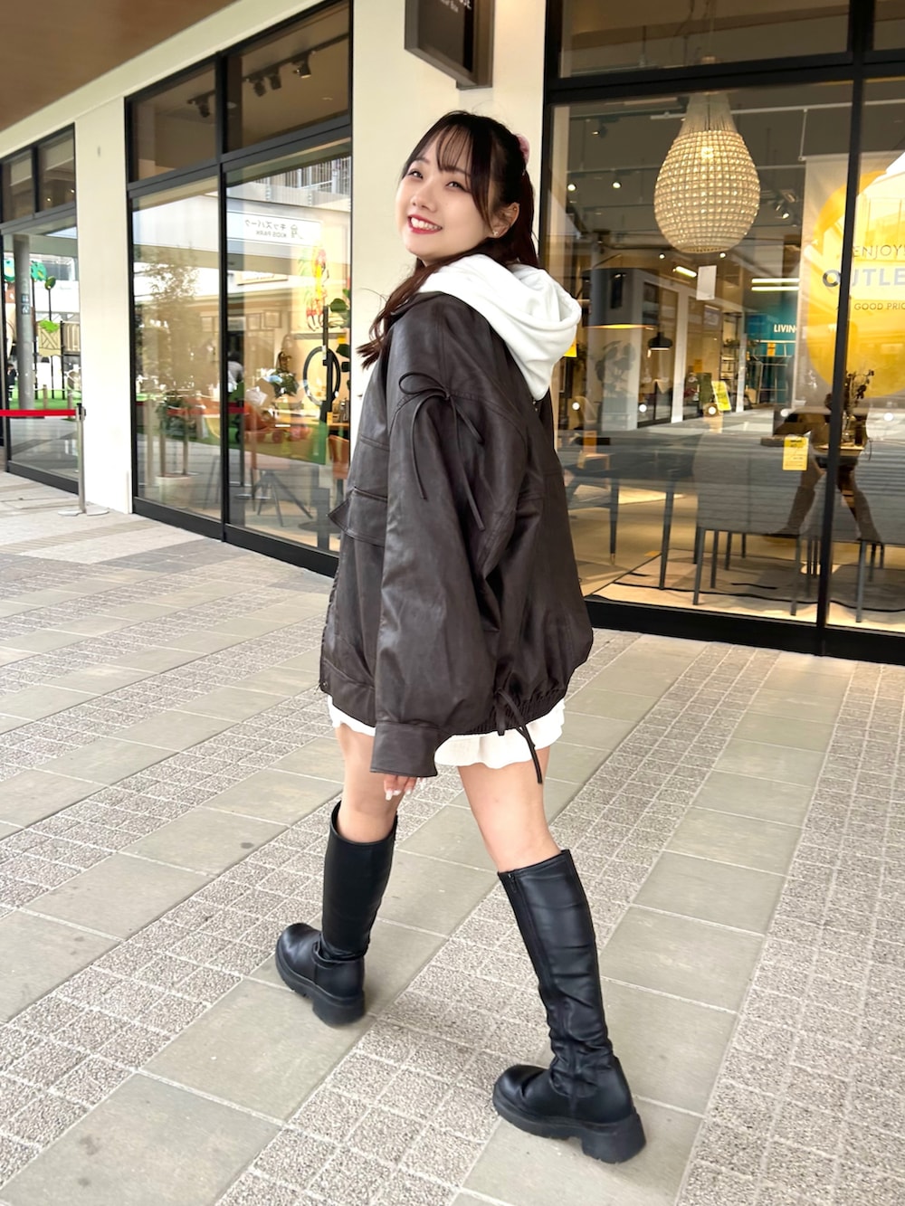 ホワイト系のパーカー、ブラウン系のブルゾン、ホワイト系のスカートを着用したレディースの冬コーディネートの2枚目の写真