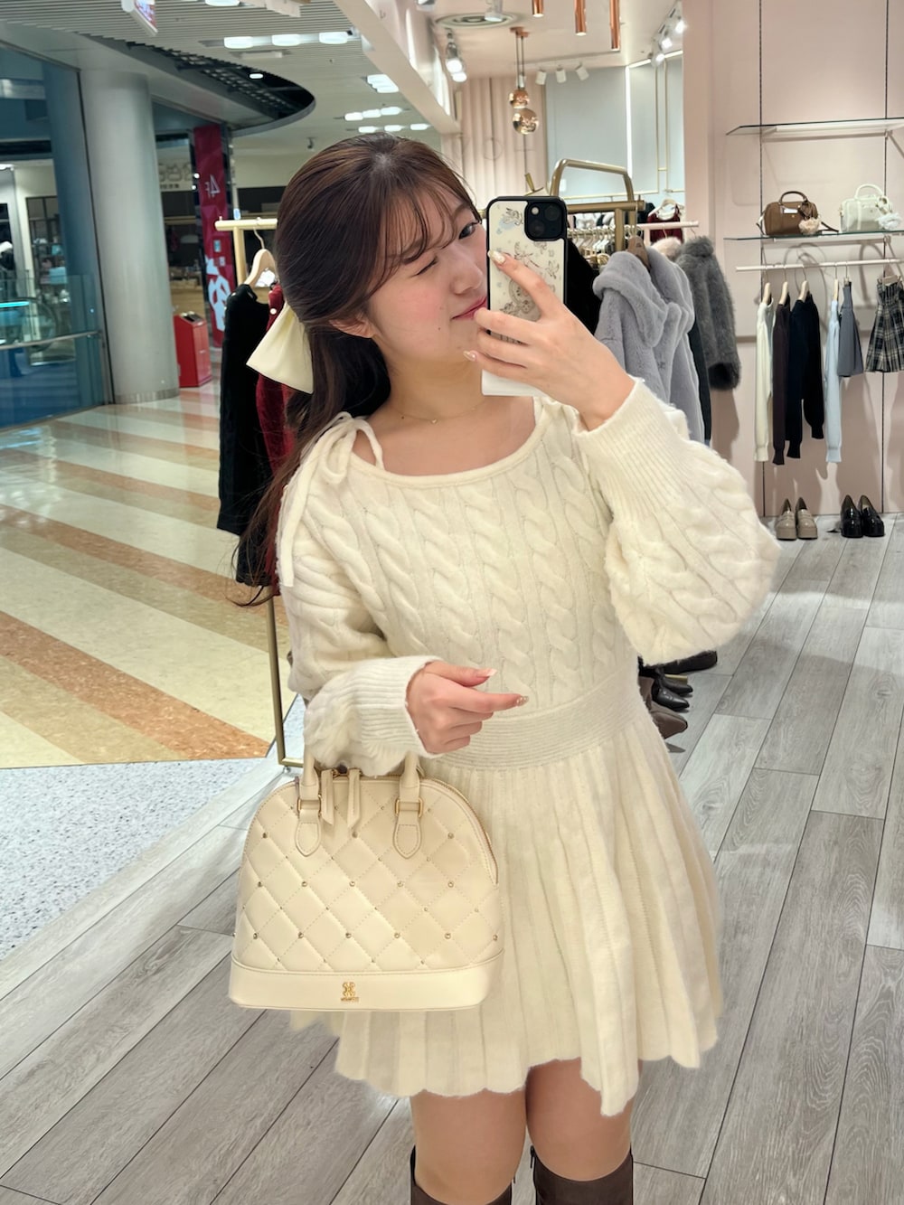 ホワイト系のワンピース、ホワイト系のハンドバッグ、ブラウン系のブーツを着用したレディースの冬コーディネートの2枚目の写真