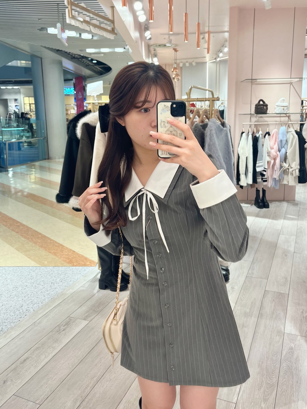 グレー系のワンピース、ホワイト系のショルダーバッグ、ブラウン系のブーツを着用したレディースの冬コーディネートの2枚目の写真