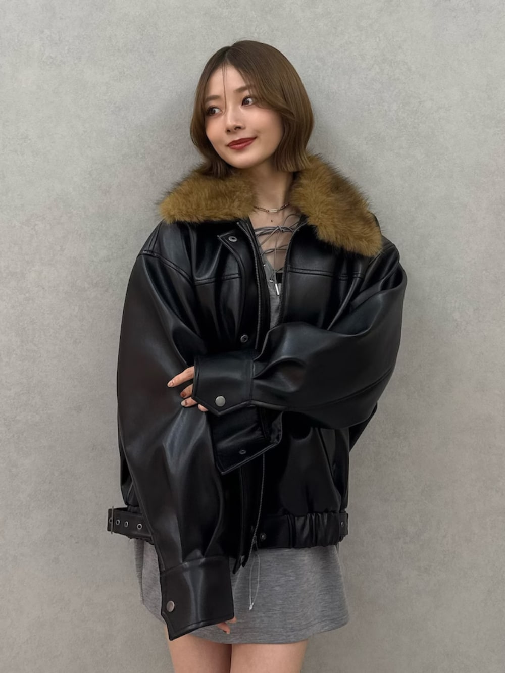 ブラック系のブルゾン、グレー系のワンピース、ブラック系のブーツを着用したレディースの冬コーディネートの3枚目の写真