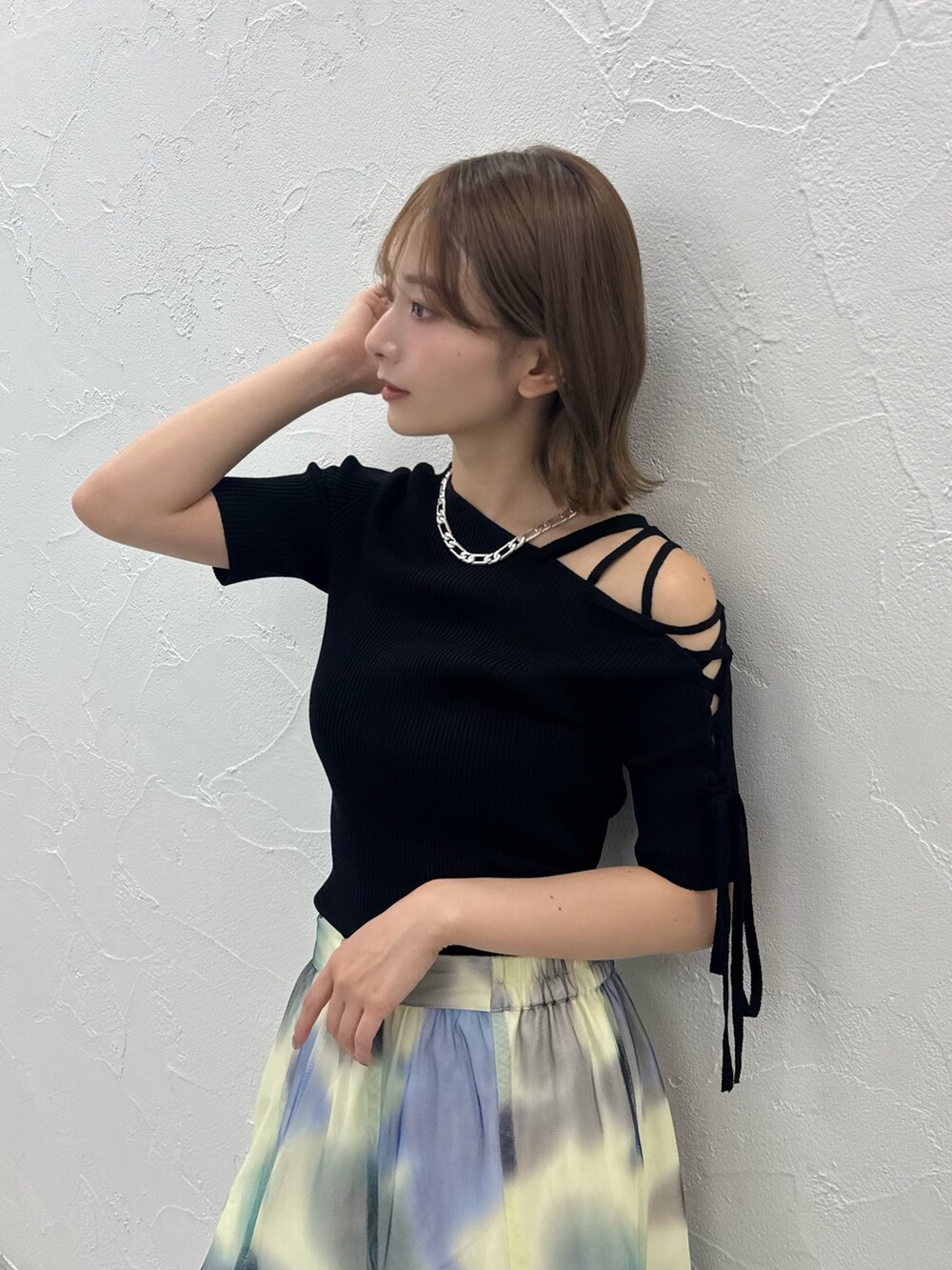 ブラック系のニット/セーター、ホワイト系のスカート、ゴールド系のサンダルを着用したレディースの夏コーディネートの2枚目の写真