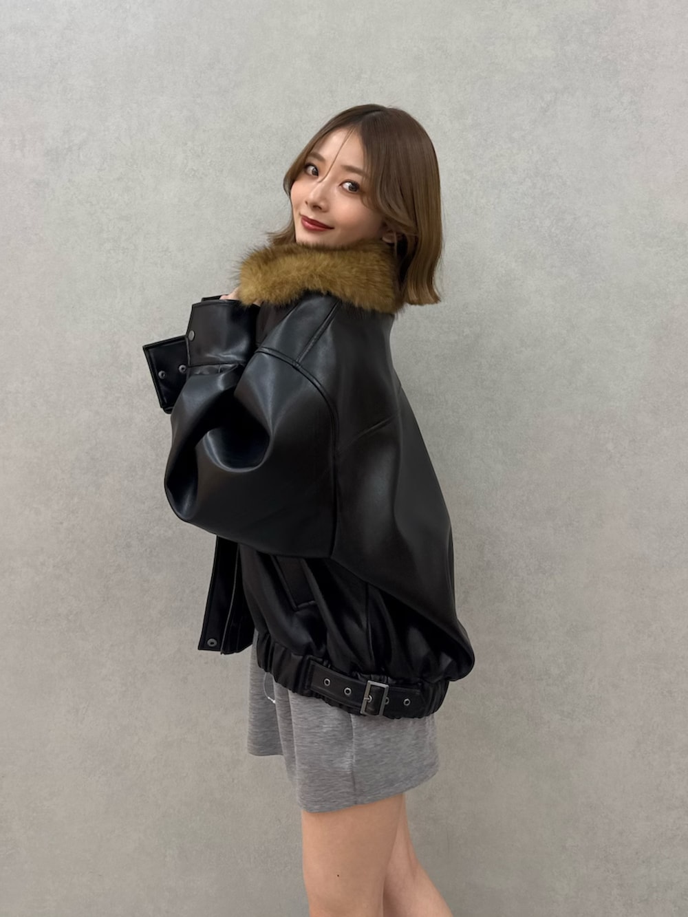 ブラック系のブルゾン、グレー系のワンピース、ブラック系のブーツを着用したレディースの冬コーディネートの5枚目の写真