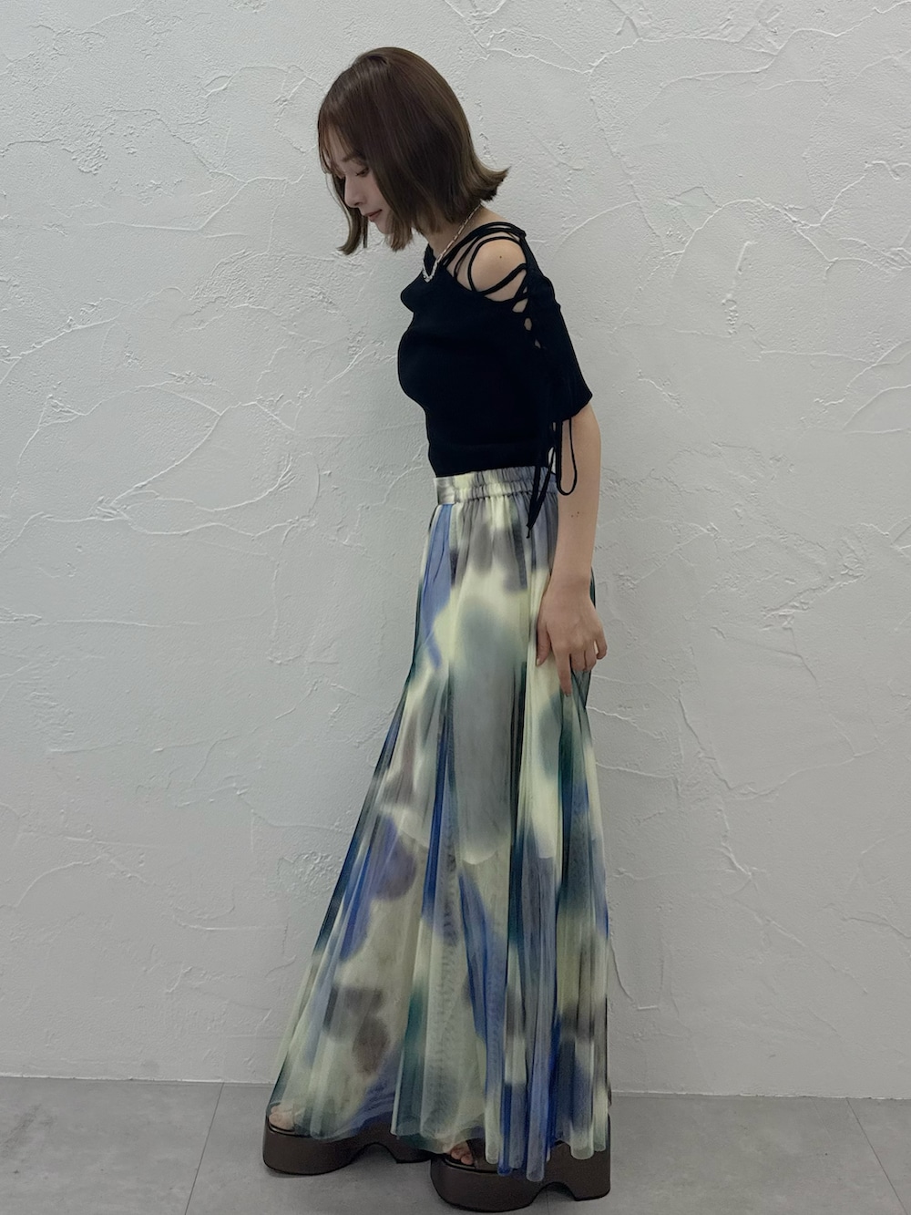 ブラック系のニット/セーター、ホワイト系のスカート、ゴールド系のサンダルを着用したレディースの夏コーディネートの3枚目の写真