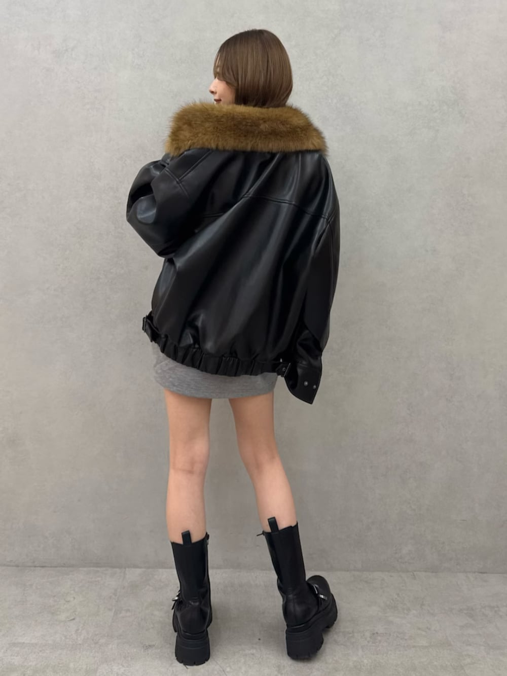 ブラック系のブルゾン、グレー系のワンピース、ブラック系のブーツを着用したレディースの冬コーディネートの4枚目の写真