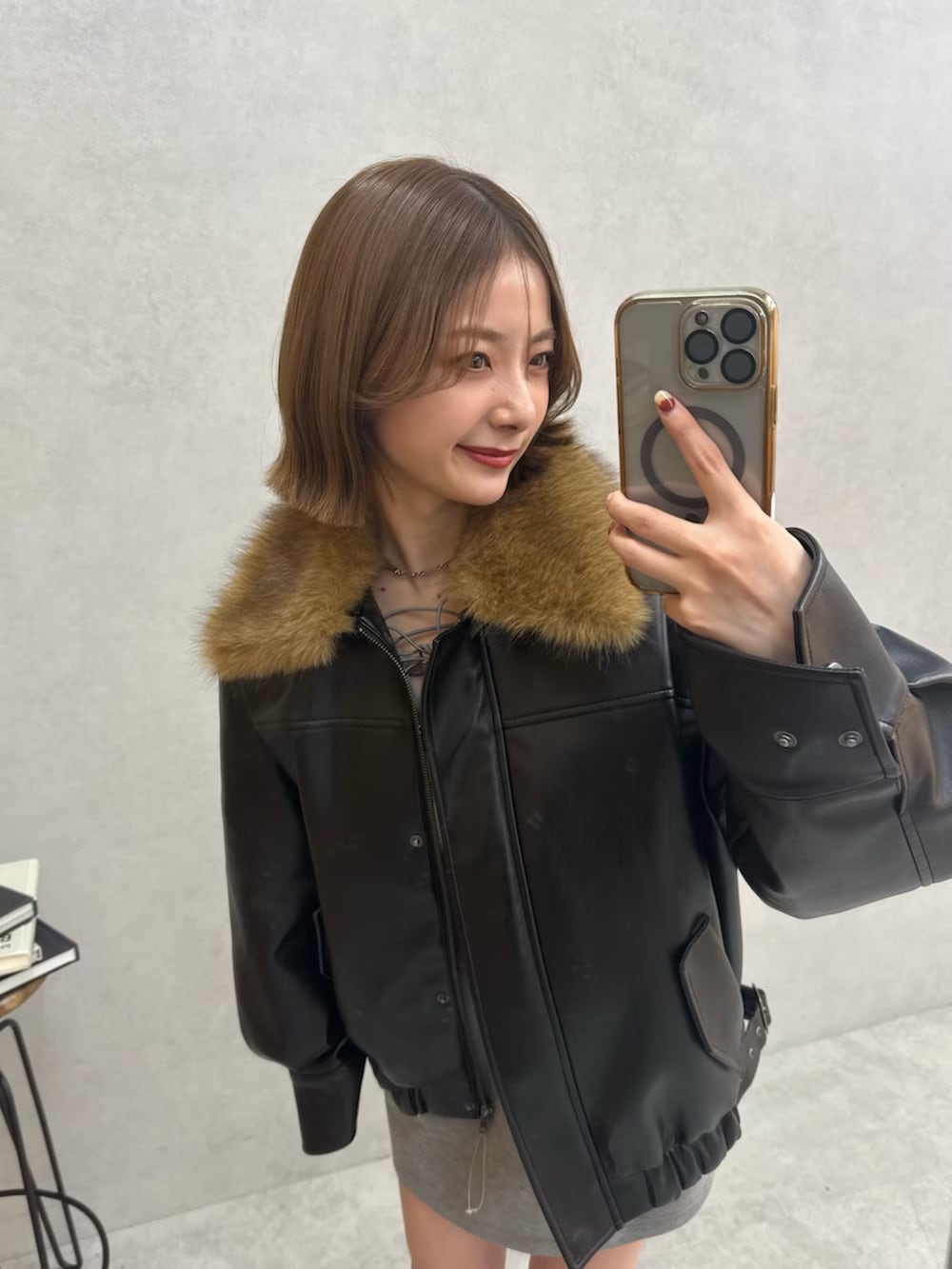 ブラック系のブルゾン、グレー系のワンピース、ブラック系のブーツを着用したレディースの冬コーディネートの9枚目の写真