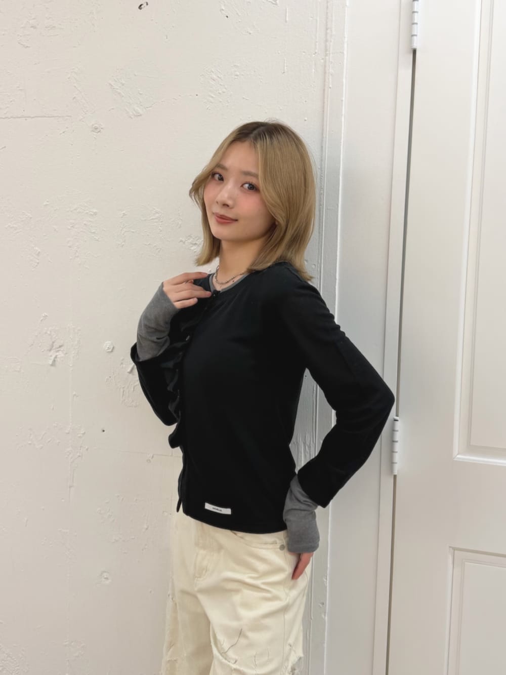 ホワイト系のデニムパンツ、ブラック系のカーディガン/ボレロ、ブラウン系のブーツを着用したレディースの春コーディネートの6枚目の写真
