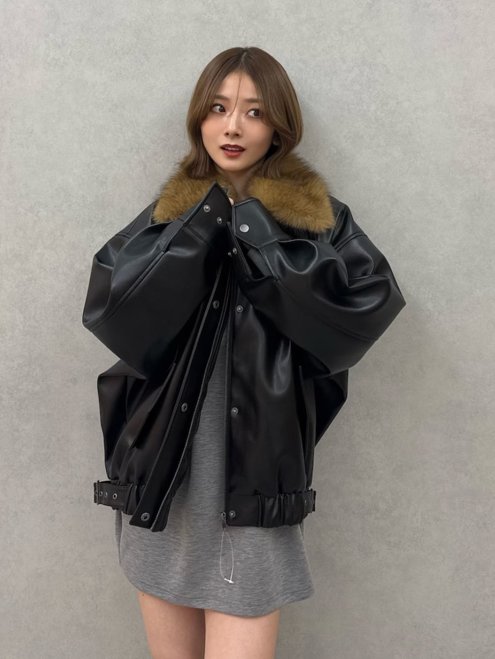 ブラック系のブルゾン、グレー系のワンピース、ブラック系のブーツを着用したレディースの冬コーディネートの7枚目の写真