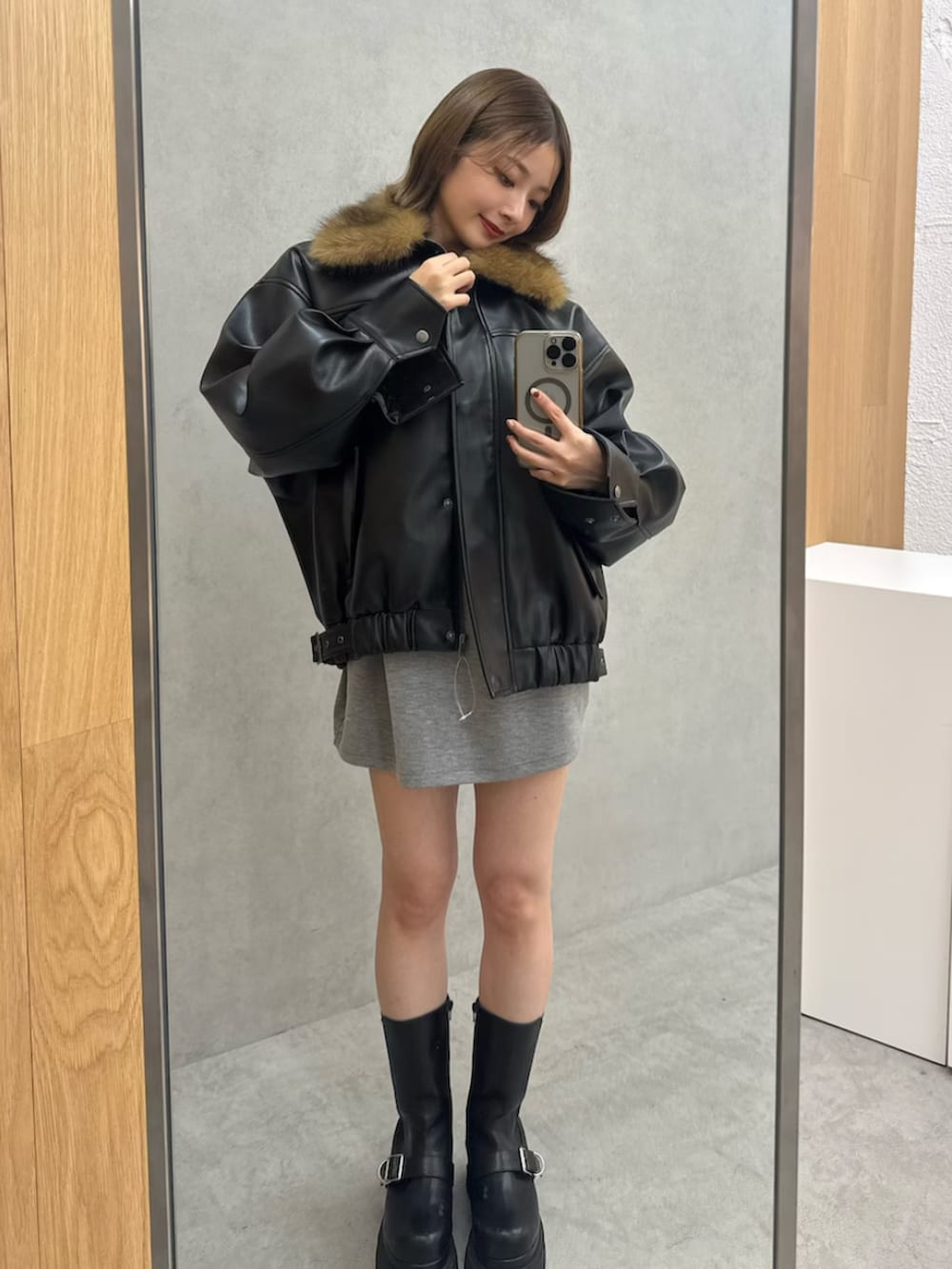 ブラック系のブルゾン、グレー系のワンピース、ブラック系のブーツを着用したレディースの冬コーディネートの8枚目の写真