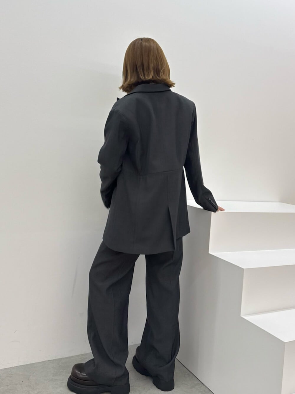 ブラウン系のサンダル、グレー系のテーラードジャケット、グレー系のスラックスを着用したレディースの夏コーディネートの4枚目の写真