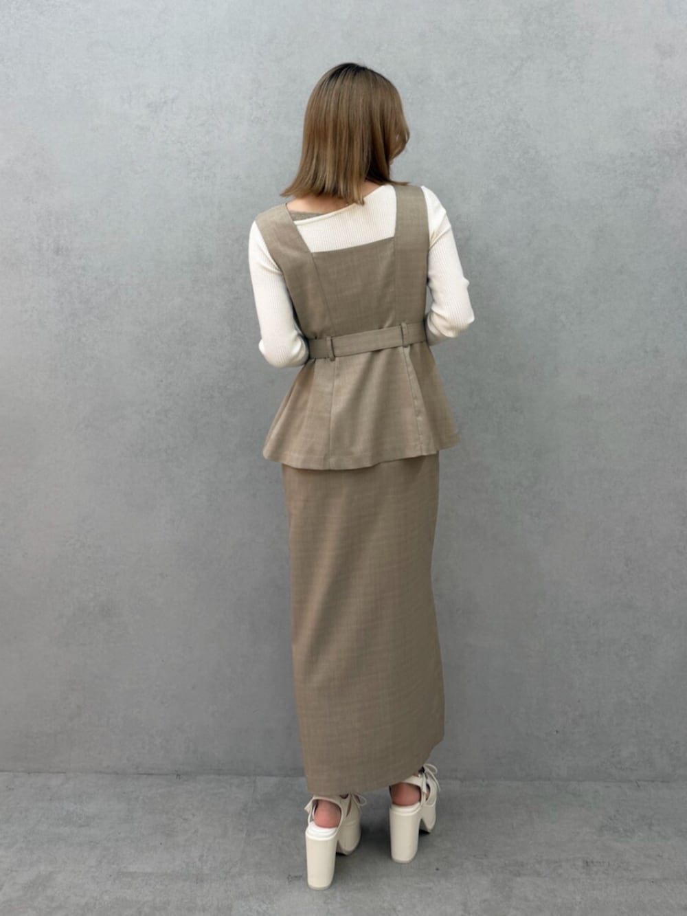 ベージュ系のジャンパースカート、ホワイト系のニット/セーター、ホワイト系のサンダルを着用したレディースの春コーディネートの4枚目の写真