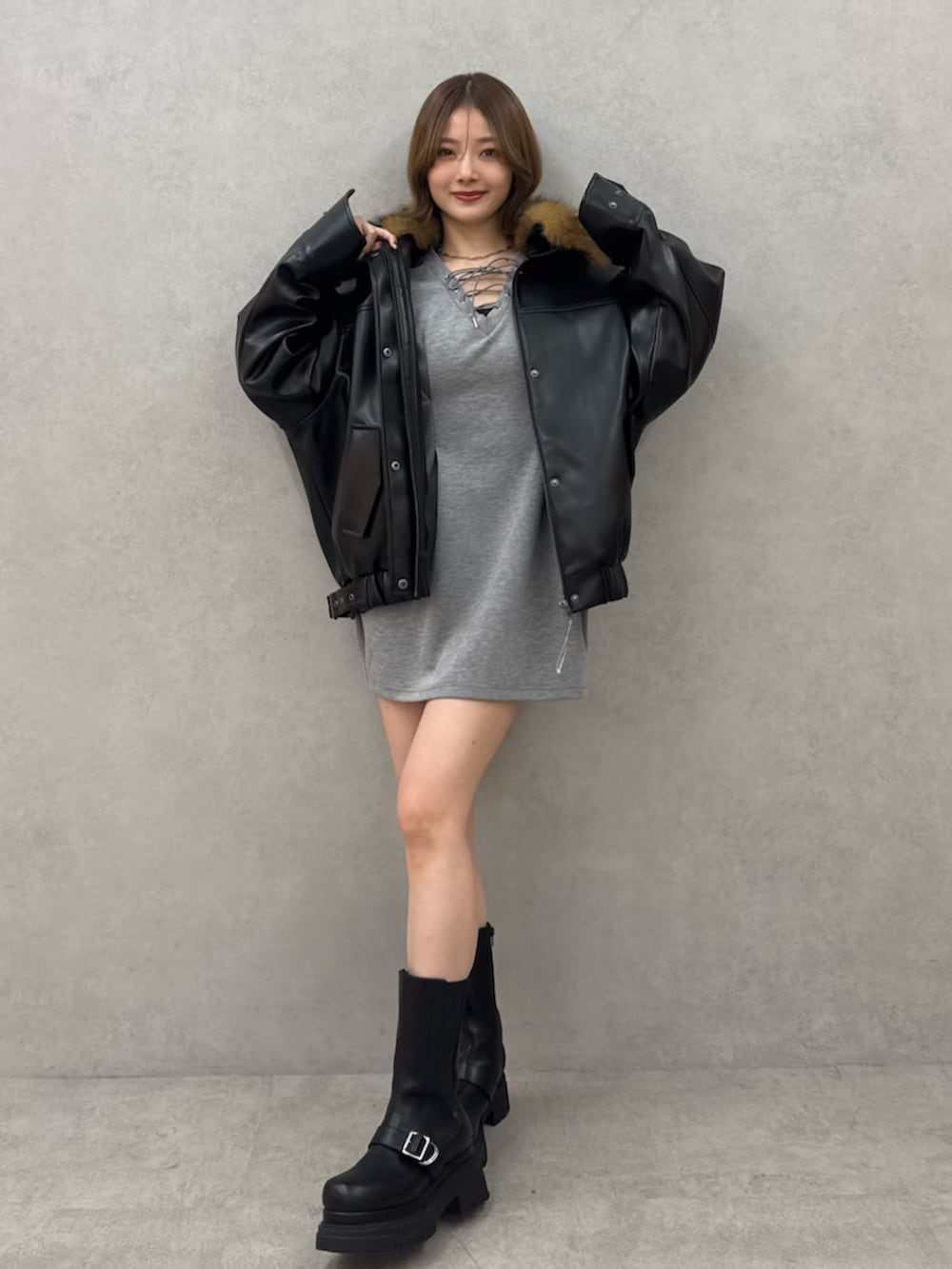 ブラック系のブルゾン、グレー系のワンピース、ブラック系のブーツを着用したレディースの冬コーディネートの2枚目の写真