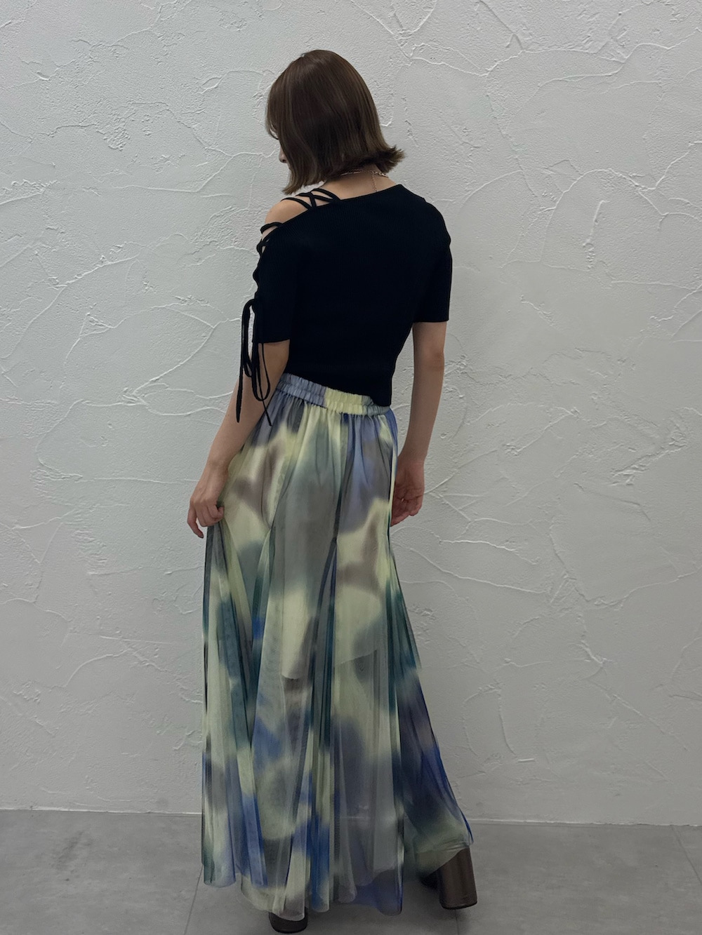 ブラック系のニット/セーター、ホワイト系のスカート、ゴールド系のサンダルを着用したレディースの夏コーディネートの4枚目の写真