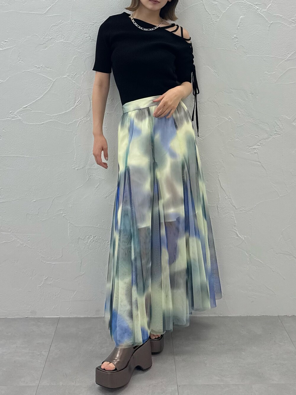 ブラック系のニット/セーター、ホワイト系のスカート、ゴールド系のサンダルを着用したレディースの夏コーディネートの5枚目の写真