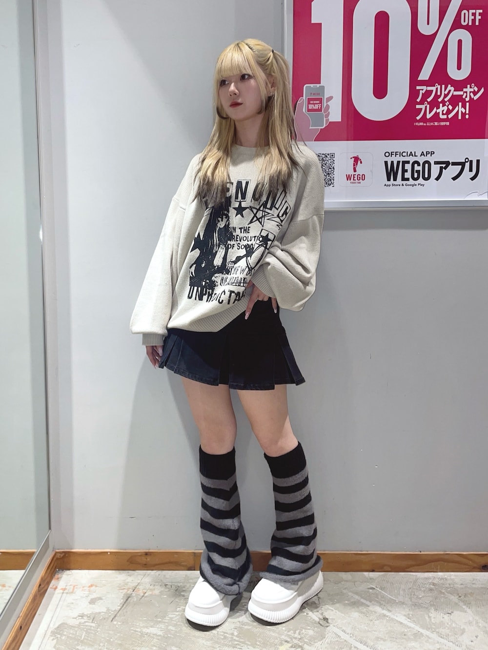 ブラック系のデニムスカート、ベージュ系のニット/セーター、ホワイト系のスニーカーを着用したレディースの秋コーディネートの2枚目の写真