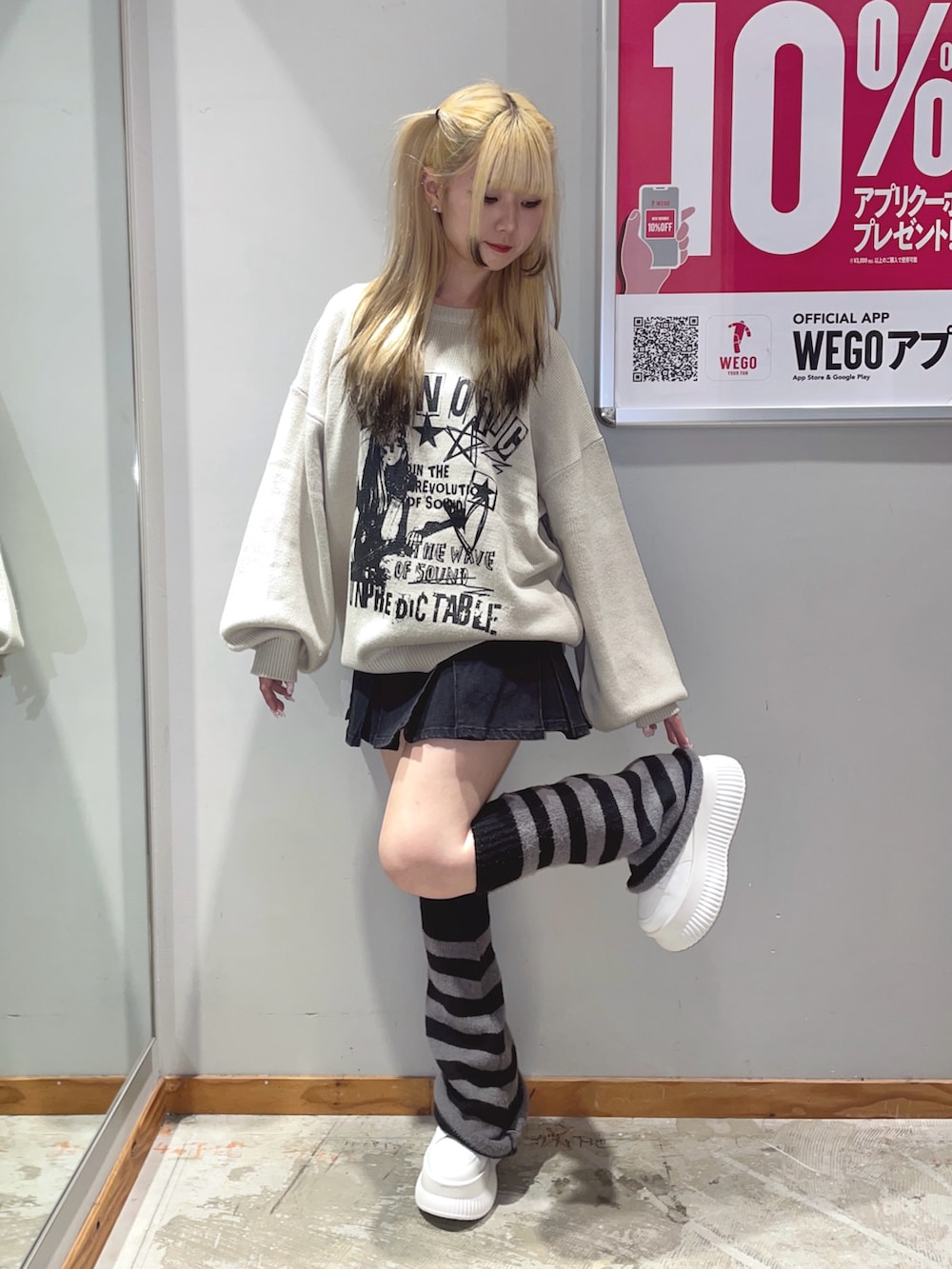 ブラック系のデニムスカート、ベージュ系のニット/セーター、ホワイト系のスニーカーを着用したレディースの秋コーディネートの3枚目の写真