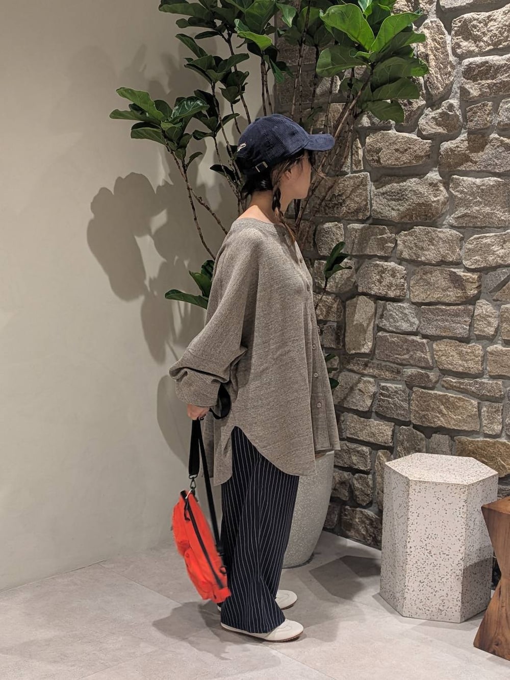 ブルー系のスラックス、ブラウン系のカーディガン/ボレロ、オレンジ系のショルダーバッグを着用したレディースの秋コーディネートの4枚目の写真