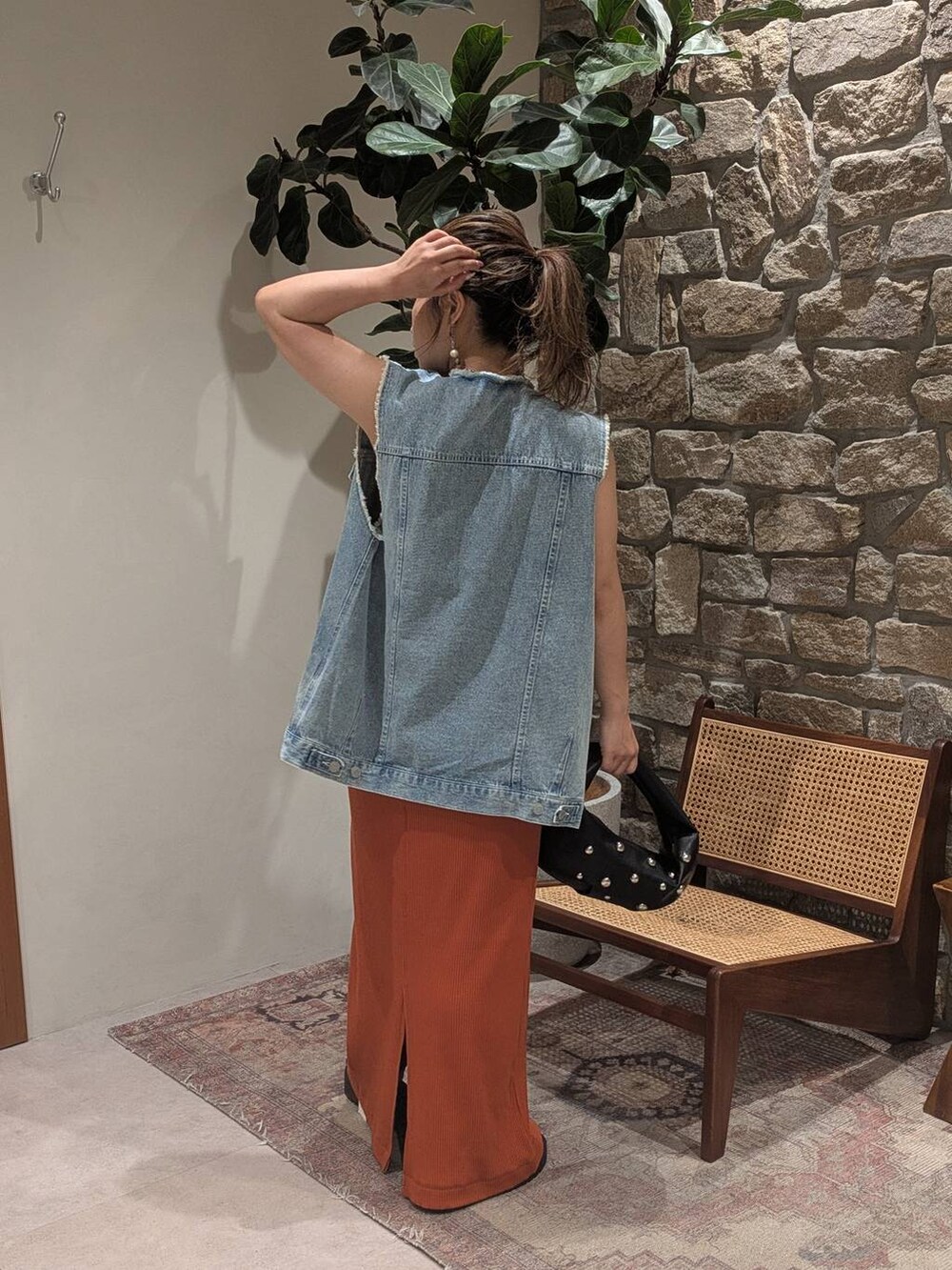 ブラック系のハンドバッグ、ブルー系のベスト、ブラック系のサンダルを着用したレディースの夏コーディネートの3枚目の写真