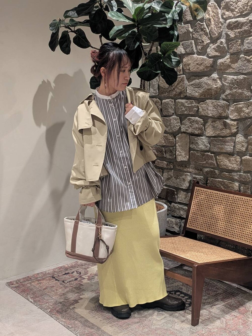 ブラウン系のブーツ、ベージュ系のトレンチコート、ブラウン系のトートバッグを着用したレディースの冬コーディネートの2枚目の写真