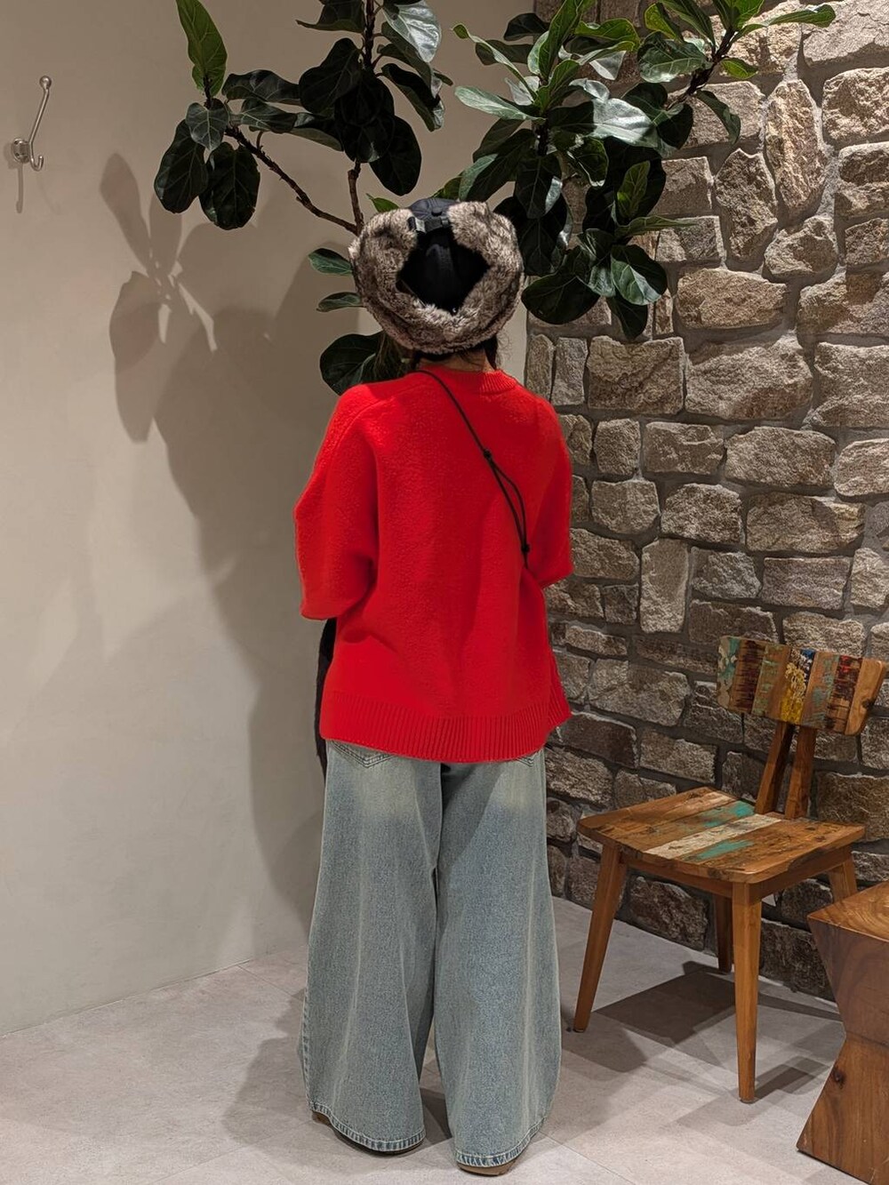 ブラウン系のショルダーバッグ、レッド系のニット/セーター、ブルー系のデニムパンツを着用したレディースの秋コーディネートの5枚目の写真