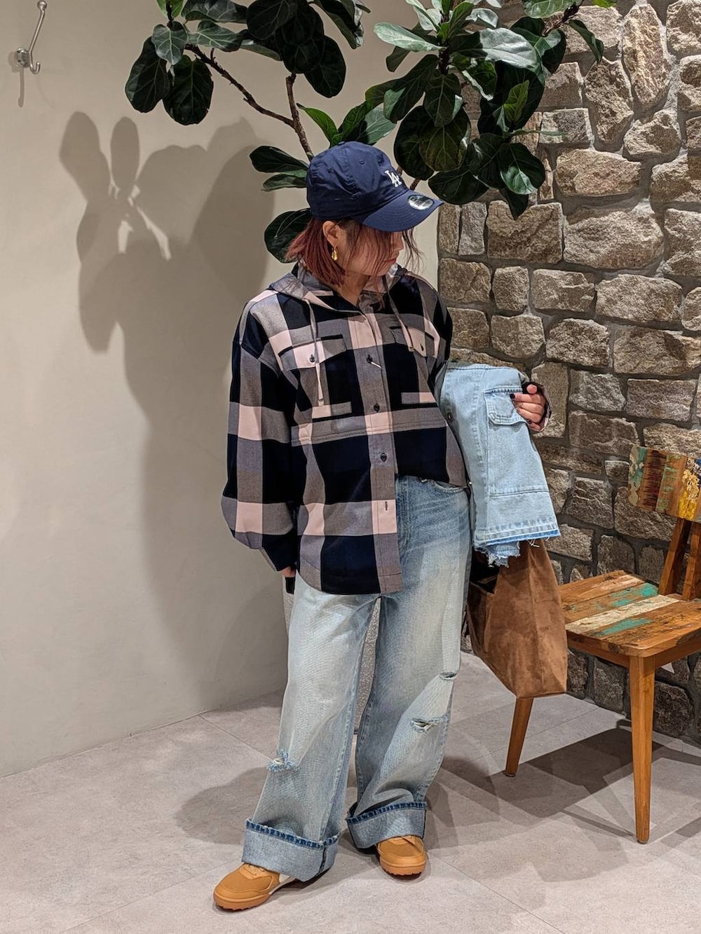 ブラウン系のトートバッグ、ブルー系のデニムパンツ、ブルー系のシャツ/ブラウスを着用したレディースの冬コーディネートの3枚目の写真