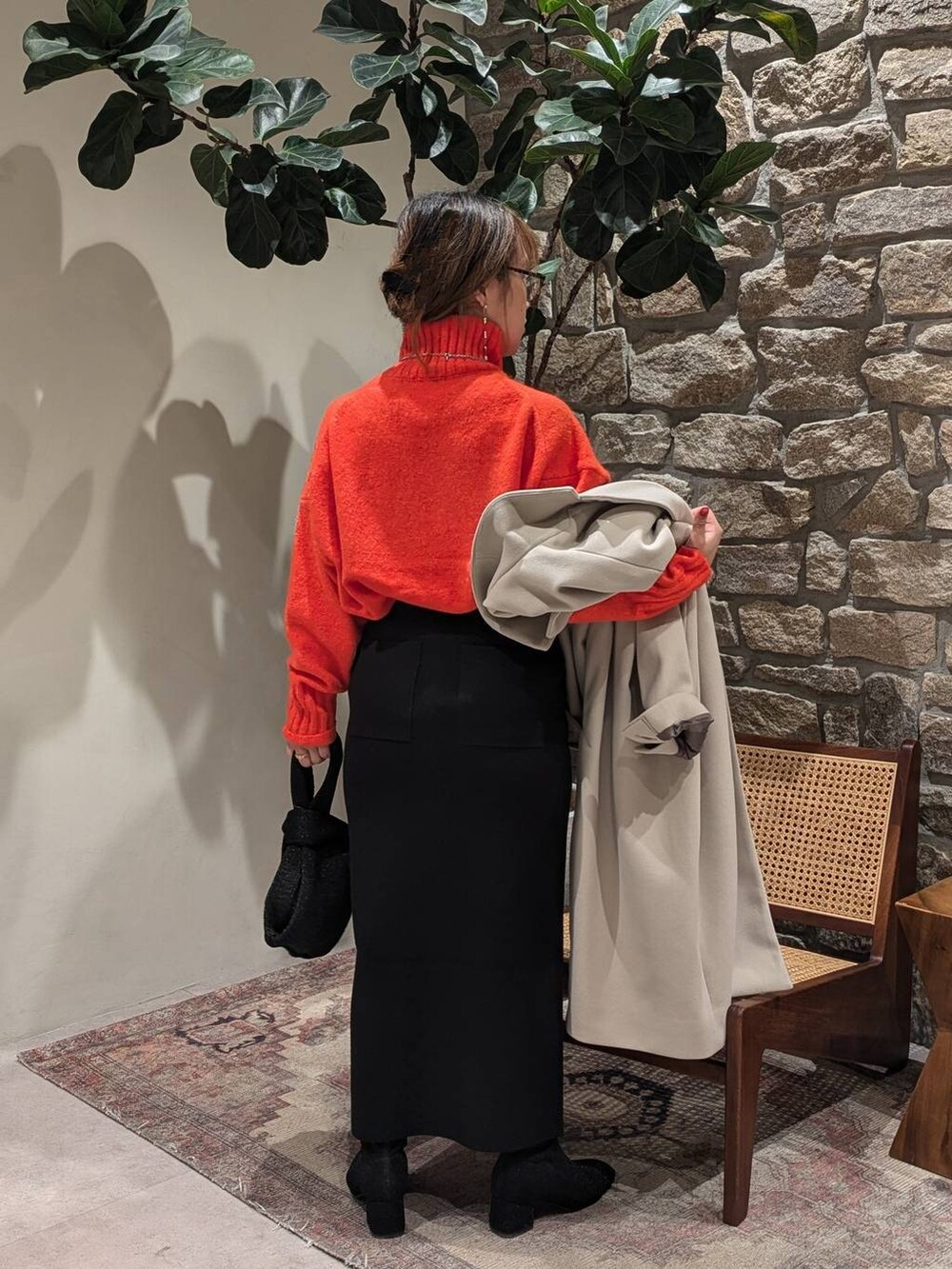 ブラック系のブーツ、オレンジ系のニット/セーター、ブルー系のハンドバッグを着用したレディースの秋コーディネートの3枚目の写真