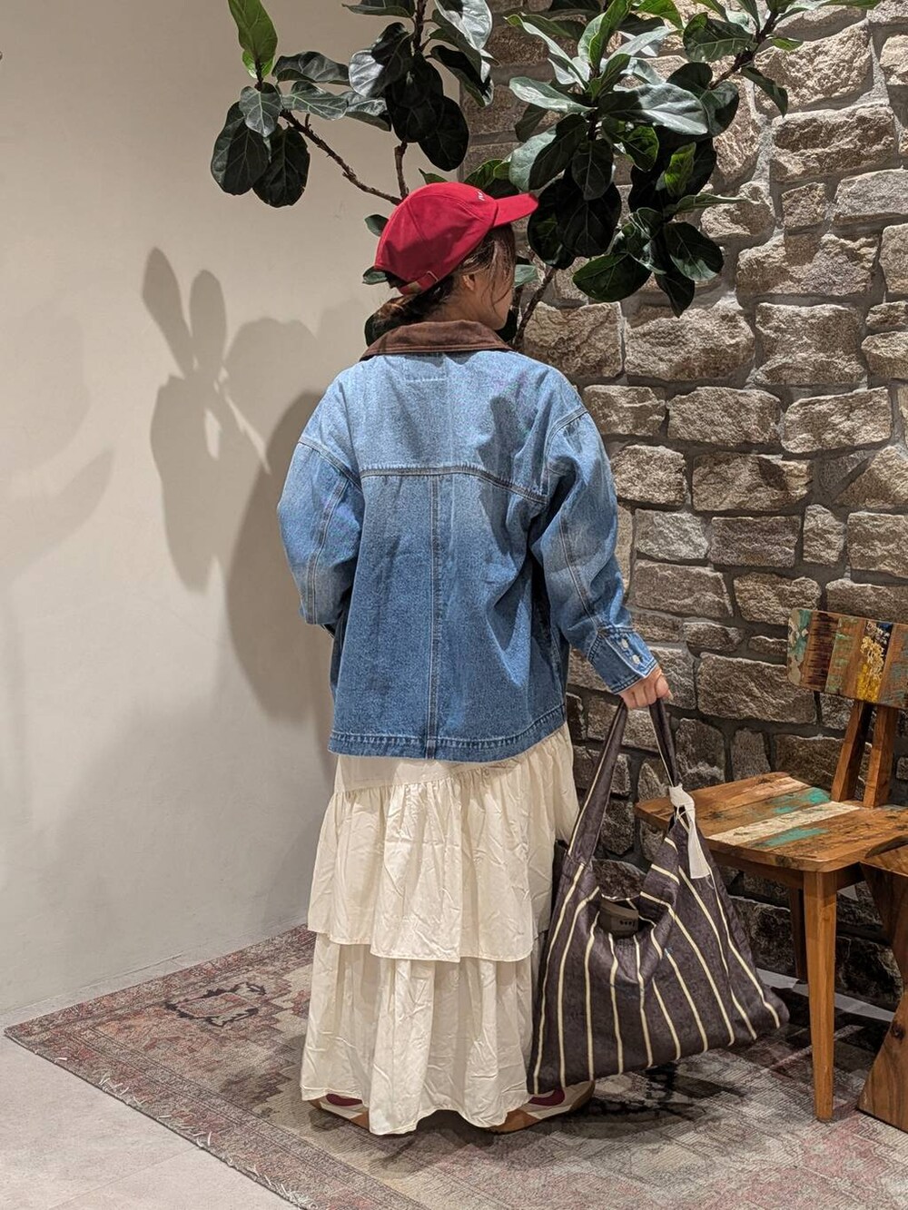 ブラウン系のトートバッグ、ブラウン系のTシャツ/カットソー、ブルー系のデニムジャケットを着用したレディースの秋コーディネートの2枚目の写真