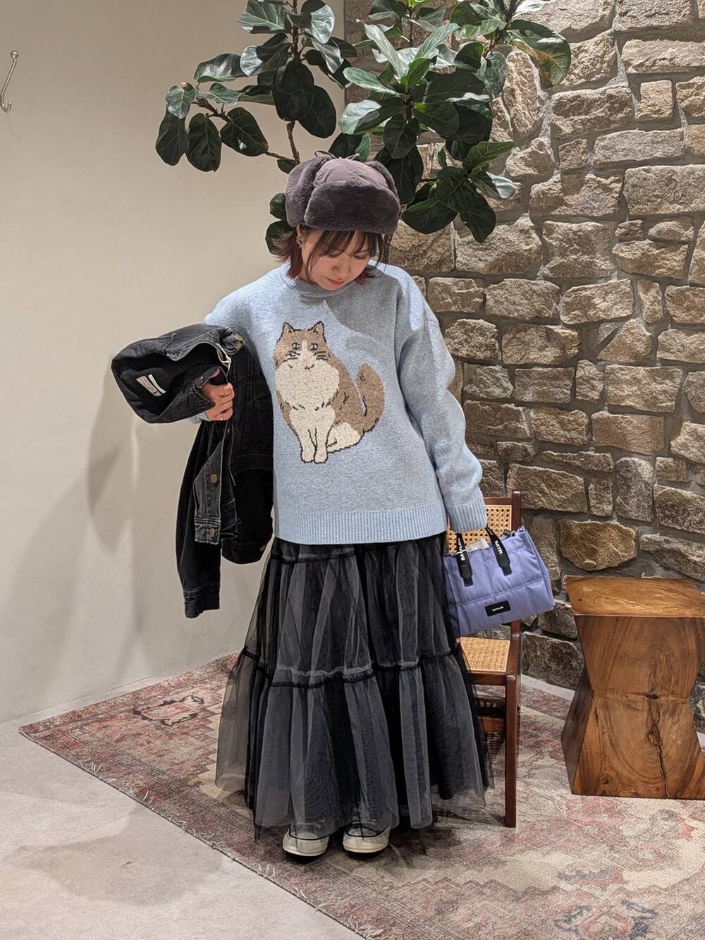 グレー系のデニムジャケット、ブルー系のニット/セーター、グレー系のスニーカーを着用したレディースの冬コーディネートの3枚目の写真