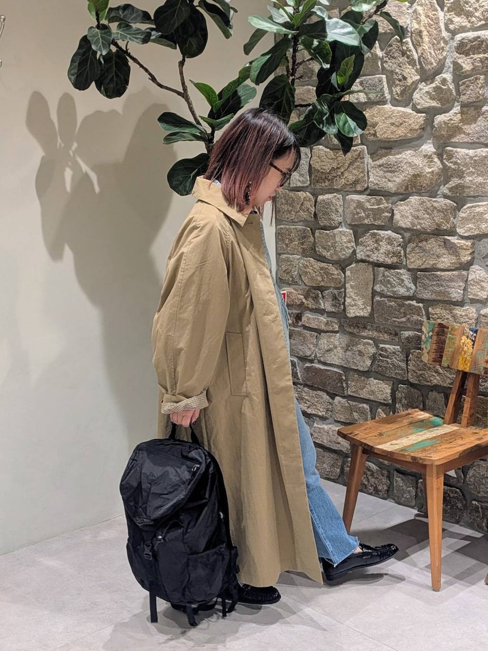 ブルー系のデニムパンツ、ブラック系のローファー、イエロー系のステンカラーコートを着用したレディースの冬コーディネートの3枚目の写真