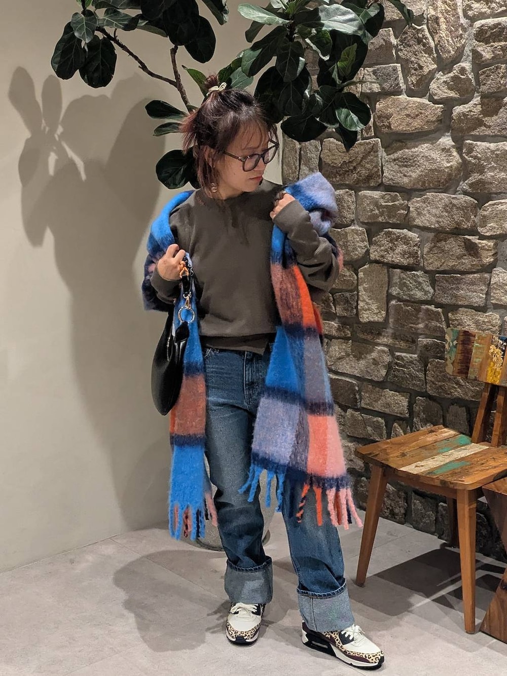 ブラック系のハンドバッグ、オレンジ系のマフラーを着用したレディースの冬コーディネートの3枚目の写真