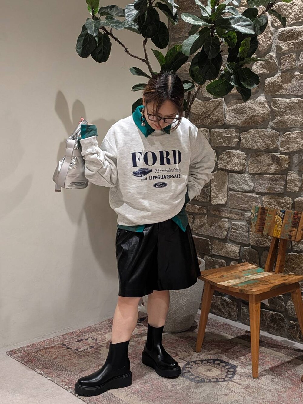 グリーン系のTシャツ/カットソー、ベージュ系のスウェット、ブラック系のブーツを着用したレディースの秋コーディネートの5枚目の写真