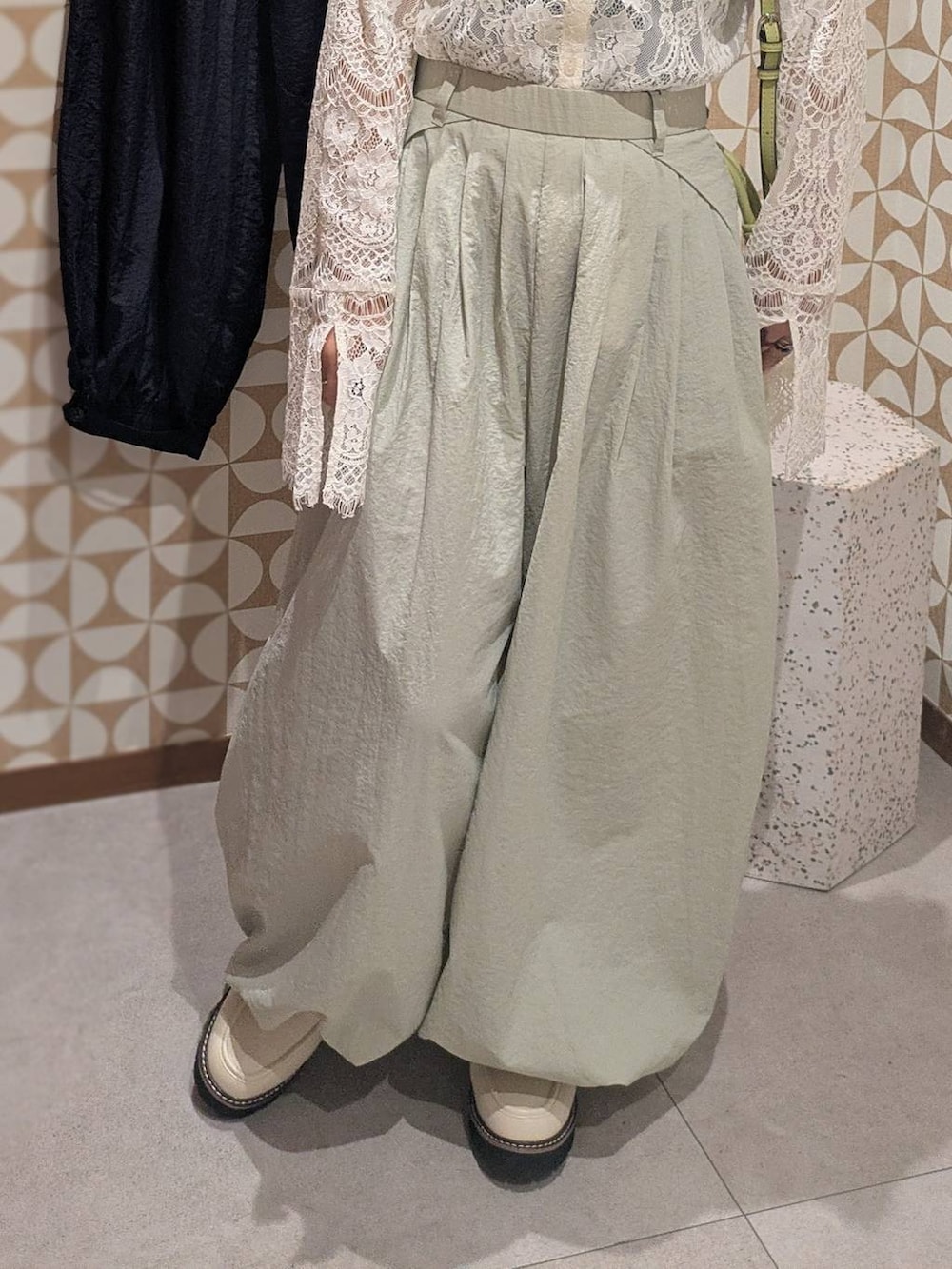 グリーン系のハンドバッグ、ホワイト系のローファー、グレー系のその他パンツを着用したレディースの冬コーディネートの4枚目の写真