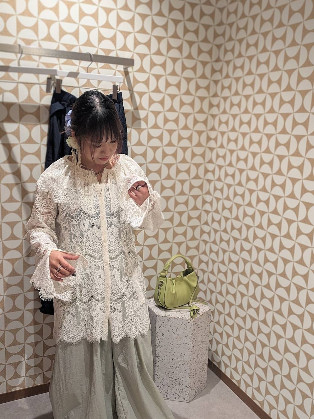 グリーン系のハンドバッグ、ホワイト系のローファー、グレー系のその他パンツを着用したレディースの冬コーディネートの2枚目の写真