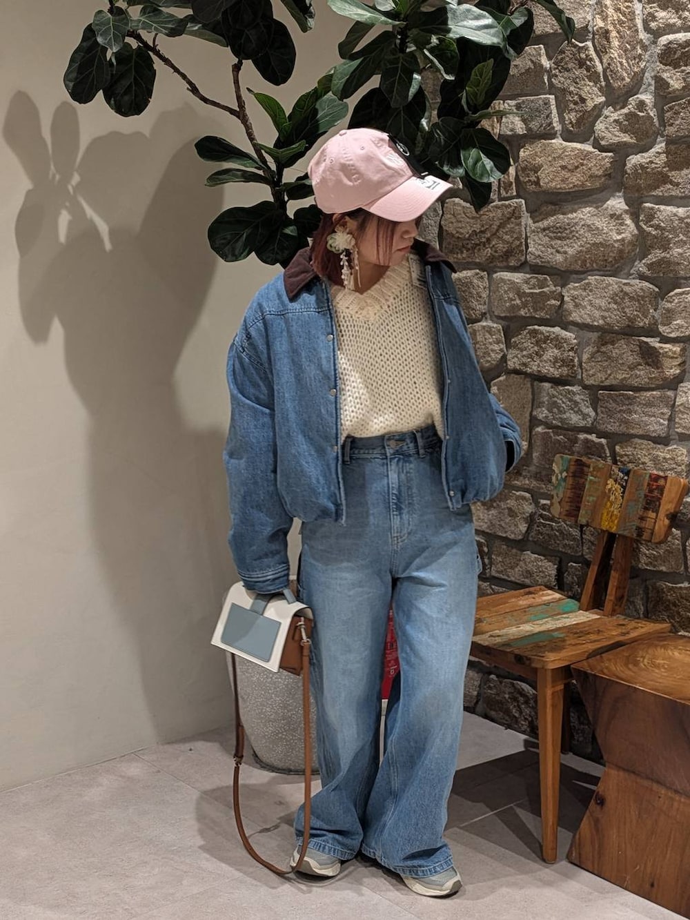 グレー系のスニーカー、ブラウン系のショルダーバッグ、ブルー系のデニムパンツを着用したレディースの冬コーディネートの5枚目の写真