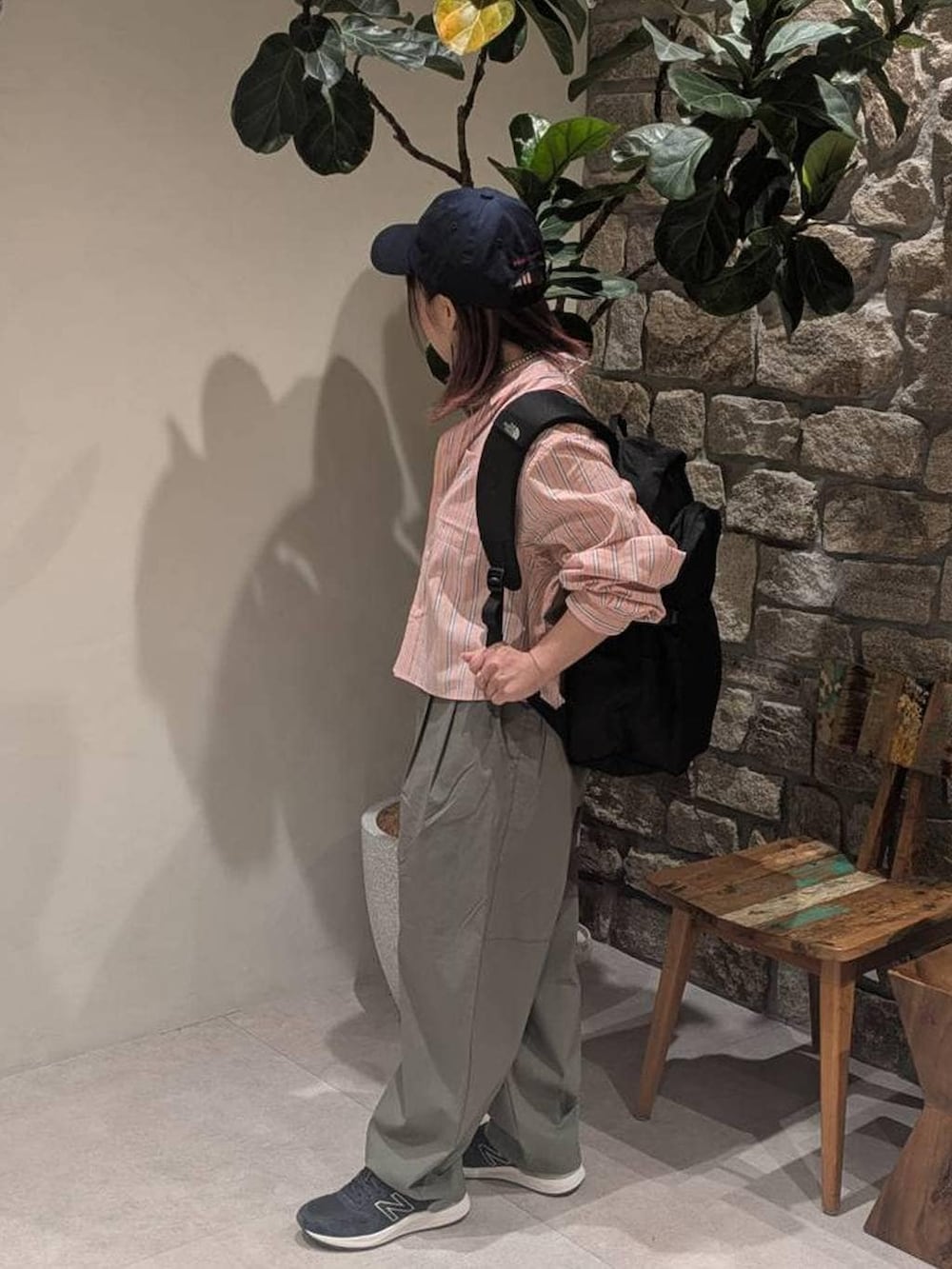 ブルー系のスニーカー、オレンジ系のシャツ/ブラウス、ブラック系のバックパック/リュックを着用したレディースの春コーディネートの2枚目の写真